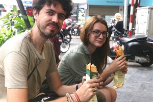 Los turistas disfrutan del banh mi de Vietnam. (Fotografía: VNA)