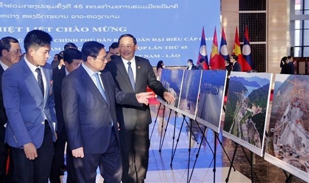Los primeros ministros Pham Minh Chinh (izquierda) y Sonexay Siphandone visitan la exposición fotográfica en Vientián. (Fotografía: VNA)