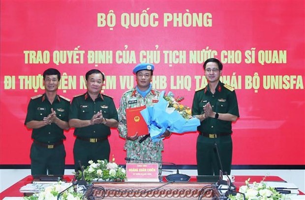 El viceministro de Defensa de Vietnam Hoang Xuan Chien entrega la Decisión del Presidente de Estado al primer coronel Dang Quoc Tuan. (Fotografía: VNA)
