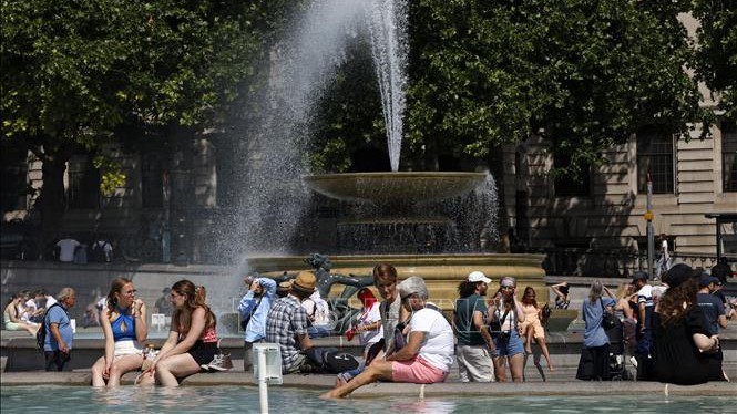 Gente alrededor de la fuente en la plaza de Trafalgar en Londres, la capital del Reino Unido, para aliviarse del calor, el 17 de junio de 2022. (Fotografía: VNA)