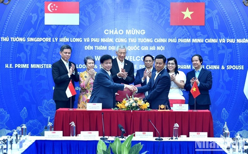 Los dos dirigentes testimonian la firma de un acuerdo de cooperación entre la Universidad Nacional de Hanói, la Universidad Nacional de Ciudad Ho Chi Minh y la Universidad Tecnológica Nanyang (Singapur). (Fotografía: VNA)