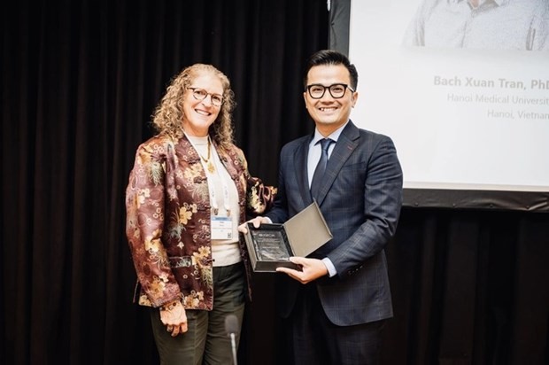 El profesor adjunto y doctor Tran Xuan Bach (derecha) recibe el premio de ISPOR. (Fotografía: nld.com.vn)