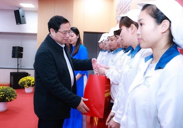 El primer ministro Pham Minh Chinh entrega obsequios a trabajadores. (Fotografía: VNA)