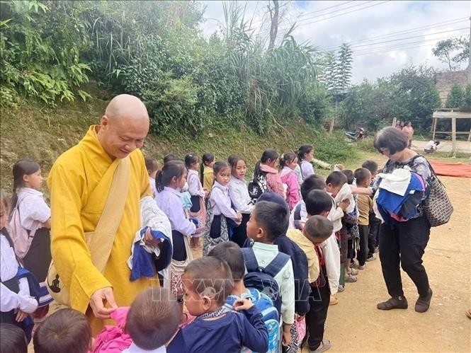 El venerable Thich Minh Quang, abad de la pagoda de Phat Tich en Vientián, obsequia a niños de familias afectadas por inundaciones en Houaphan. (Fotografía: VNA)