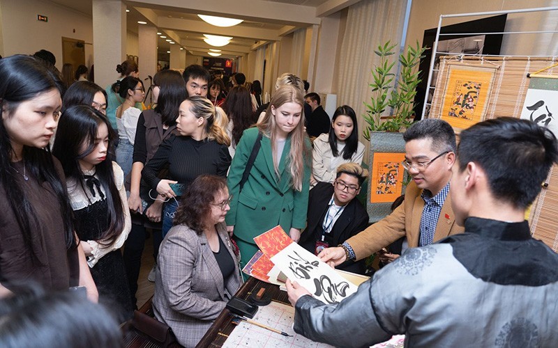 Estudiantes internacionales aprenden sobre caligrafía en el Festival de Vietnam en Rusia.