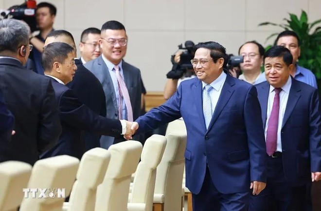 El primer ministro de Vietnam, Pham Minh Chinh (en la derecha), estrecha la mano de empresario chino. (Fotografía: VNA)