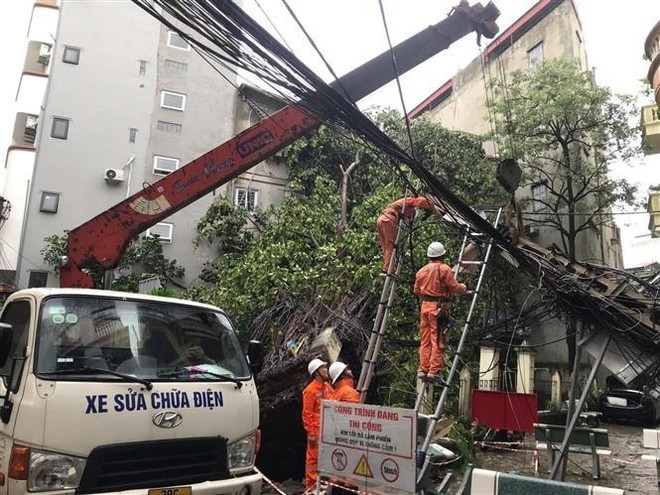 Electricistas reparan los postes de luz caídos a causa de la tormenta. (Foto: VNA)