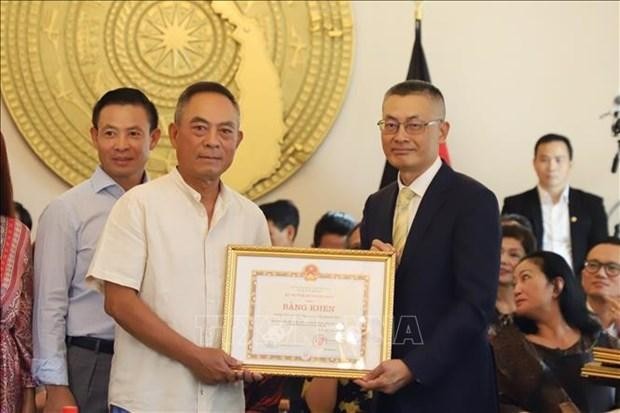 El embajador vietnamita enAlemania, Vu Quang Minh (derecha), entrega los certificados de mérito del Ministro de Relaciones Exteriores a un representante del Centro Dong Xuan en Berlín. (Fotografía: VNA)