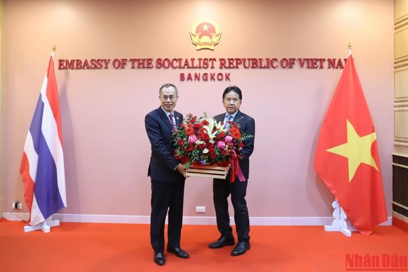 El embajador laosiano en Tailandia, Khamphan Anlavan entrega flores a su par veitnamita.