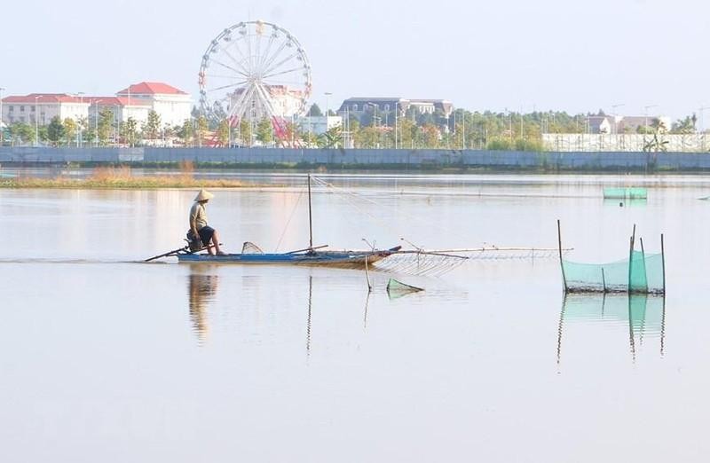 Un residente del distrito de Vi Thuy pesca en campos inundados.