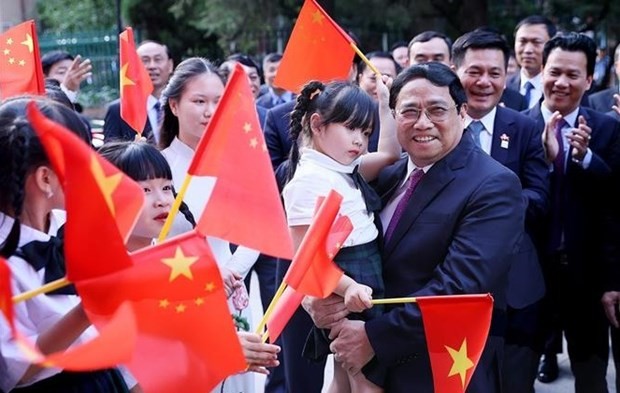 El primer ministro de Vietnam, Pham Minh Chinh, y representantes de la comunidad de connacionales en China (Fotografía: VNA)