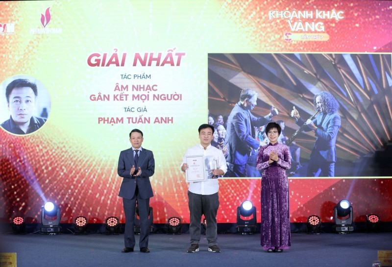 La directora general de la VNA, Vu Viet Trang (derecha), y el vicepresidente permanente de la Asociación de Periodistas de Vietnam, Nguyen Duc Loi (izquierda), entregan el primer premio a Pham Tuan Anh en el evento. (Foto: VNA)