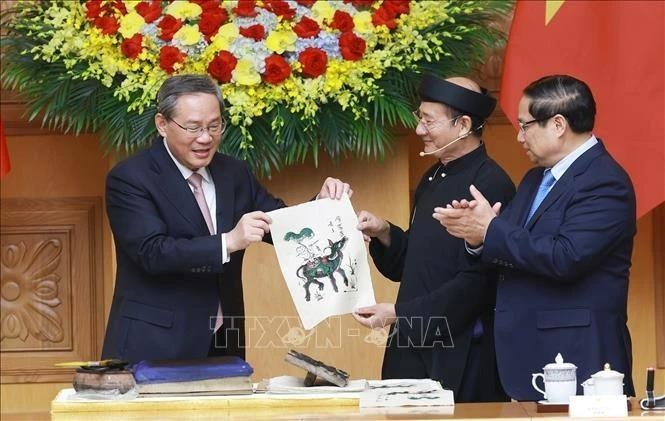 El primer ministro vietnamita, Pham Minh Chinh (derecha), y su par chino, Li Qiang, experimentaron de primera mano la creación de una pintura popular de Dong Ho. (Foto: VNA)