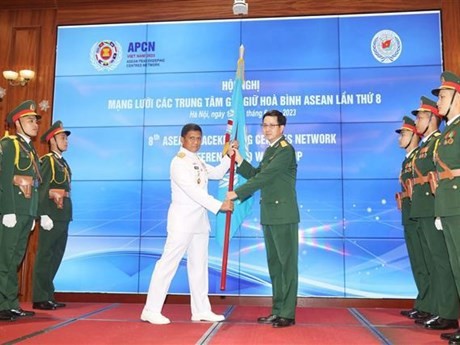 El Coronel Pham Manh Thang, director del Departamento de Mantenimiento de la Paz de Vietnam (derecha), entrega la bandera de la APCN al jefe de la delegación militar de Indonesia (Foto: VNA)