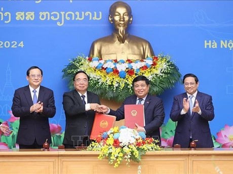 El primer ministro vietnamita, Pham Minh Chinh (primero, derecha), y su homólogo laosiano, Sonexay Siphandone (primero, izquierda), presencian la firma del acta de la reunión. (Foto: VNA)