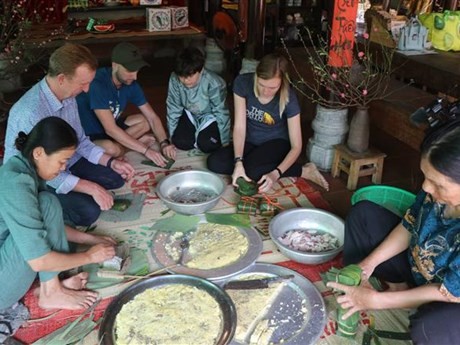 Turistas extranjeros participan en la elaboración de banh chung (pastel cuadrado de arroz glutinoso) (Fuente:VNA)