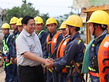 El primer ministro Pham Minh Chinh y los trabajadores que construyen el puente Nguyen Hoang sobre el río Huong. (Foto: VNA)