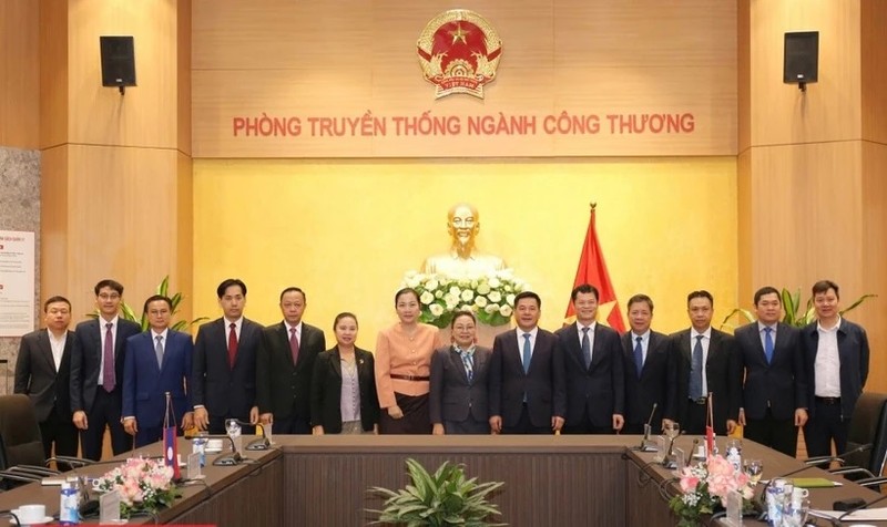 El ministro de Industria y Comercio, Nguyen Hong Dien (sexto desde la derecha), y la embajadora de Laos en Vietnam, Khamphao Ernthavanh (séptima desde la derecha), mantienen una sesión de trabajo. (Fotografía: tapchicongthuong.vn)