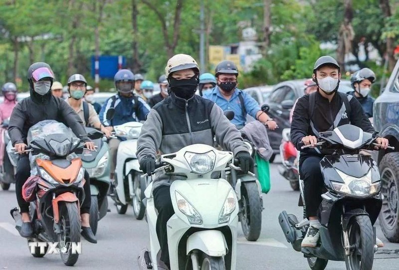 Motociclistas visten ropa abrigada y guantes al circular en la calle. (Fotografía: VNA)