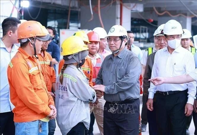 El primer ministro Pham Minh Chinh (segundo desde la derecha) felicita por el Año Nuevo a los trabajadores de la obra de construcción de la Terminal 3 del Aeropuerto Internacional de Tan Son Nhat, en Ciudad Ho Chi Minh. (Fotografía: VNA)