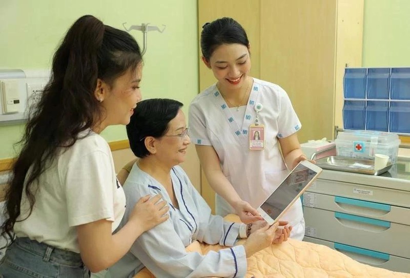 El personal médico utiliza una tableta para compartir información con una paciente. (Fotografía: VNA)