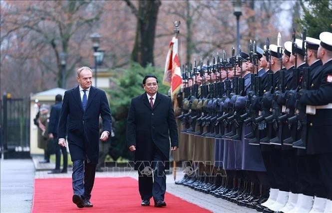 El primer ministro de Polonia, Donald Tusk, y su homólogo vietnamita, Pham Minh Chinh, pasan revista a la guardia de honor. (Foto: VNA)