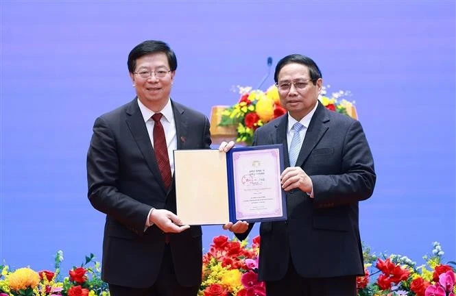 Qiu Yong (izquierda), secretario del Comité del Partido Comunista de China en la Universidad de Tsinghua, entrega el título de "Profesor Honorario" al primer ministro Pham Minh Chinh. (Foto: VNA)