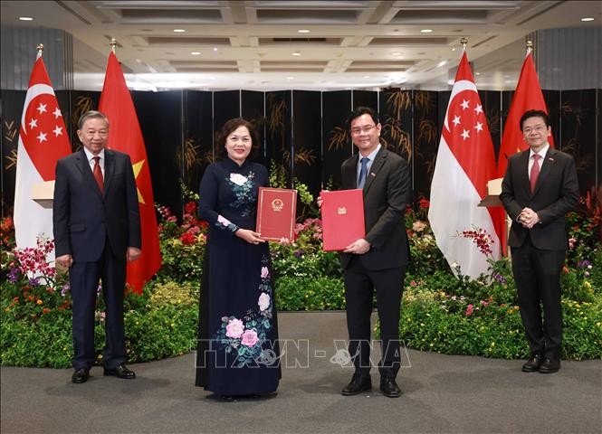 El secretario general PCV, To Lam, y el primer ministro y secretario general del gobernante Partido de Acción Popular de Singapur, Lawrence Wong, presencian la firma del Memorando de Entendimiento sobre cooperación en innovación financiera entre el Banco Estatal de Vietnam y la Autoridad Monetaria de Singapur. (Foto: VNA)