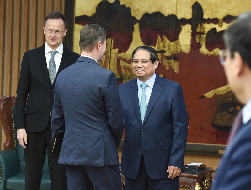 El primer ministro Pham Minh Chinh saluda a los miembros que acompaña al ministro de Asuntos Exteriores y Comercio Exterior de Hungría, Szijjarto Peter.