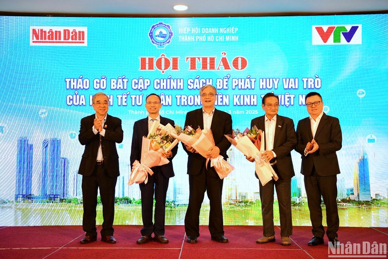 Le Quoc Minh, subjefe de la Comisión de Propaganda y Movilización de Masas del Comité Central del PCV, presidente-editor del periódico Nhan Dan y presidente de la Asociación de Periodistas del país, y el presidente de la Asociación Empresarial de Ho Chi Minh, Nguyen Ngoc Hoa, presentan flores para agradecer a los expertos que asisten al taller.