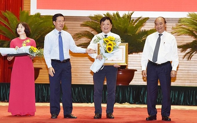 El primer ministro de Vietnam, Nguyen Xuan Phuc, entrega el certificado de mérito al representante del periódico Nhan Dan.