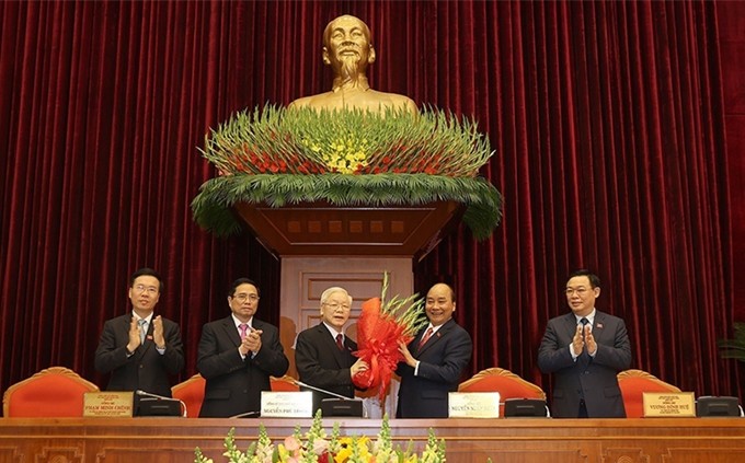 En nombre del Buró Político, el primer ministro Nguyen Xuan Phuc (segundo, derecho) felicita a Nguyen Phu Trong por ser reelegido como secretario general del PCV. (Fotografía: VNA)