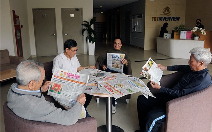 Residentes en el edificio de apartamentos T&T Riverview, en el distrito de Hoang Mai, Hanói, leen el periódico Nhan Dan. (Fotografía: Dang Khoa)