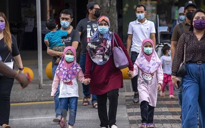 Los pobladores malasios se usan mascarrillas para prevenir contra la pandemia del Covid-19. (Fotografía: VNA)