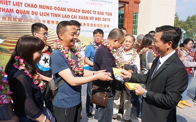 Las autoridades del Departamento de Cultura, Deportes y Turismo de la provincia Lao Cai regalan flores y regalos a los turistas chinos.