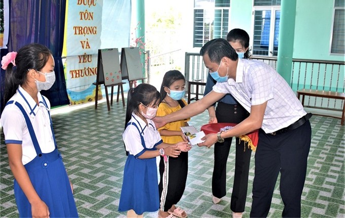 Un representante de la corresponsalía de Nhan Dan en Can Tho entrega becas a los estudiantes en Phu Tan. (Fotografía: Nhan Dan)