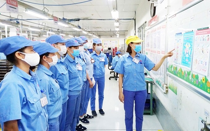 La sociedad anónima FWCC Sowa en el parque industrial de Thang Long, distrito de Dong Anh, difunde sobre las medidas preventivas de la pandemia a los obreros.