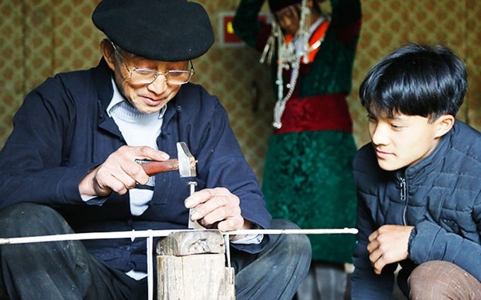 El artesano Mua Se Sinh enseña a los jóvenes la técnica de trabajar la plata.