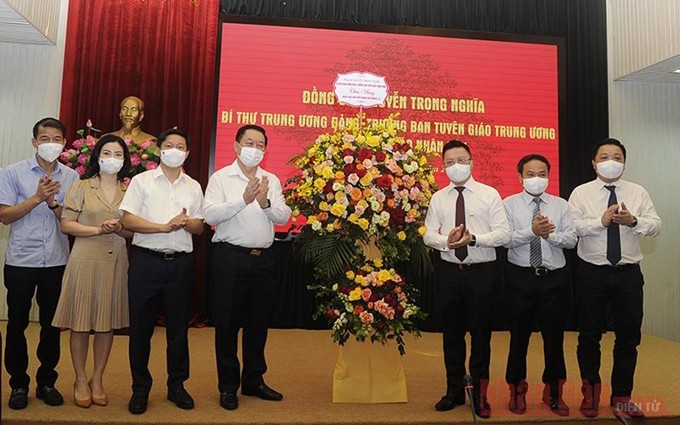 El jefe de la delegación visitante, Nguyen Trong Nghia (cuarto desde la izquierda), entrega flores de felicitación con motivo de la efeméride a los representantes de Nhan Dan. (Fotografía: Nhan Dan)