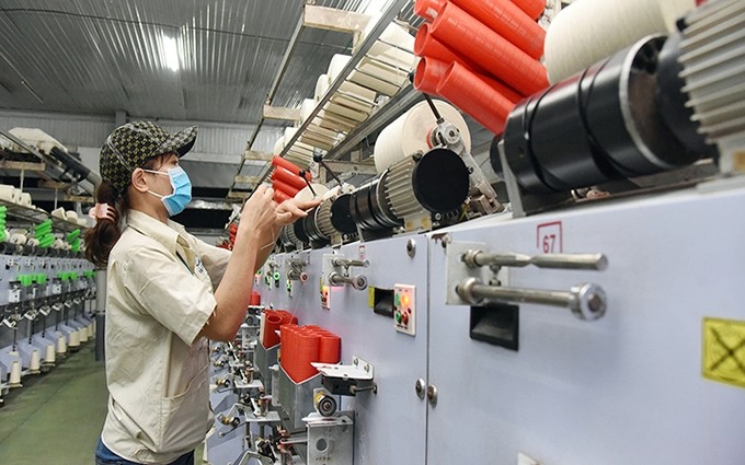 Una trabajadora de la empresa de Textiles Ha Nam, en el Parque Industrial de Chau Son, provincia norteña de Ha Nam, opera una línea de producción de hilo.