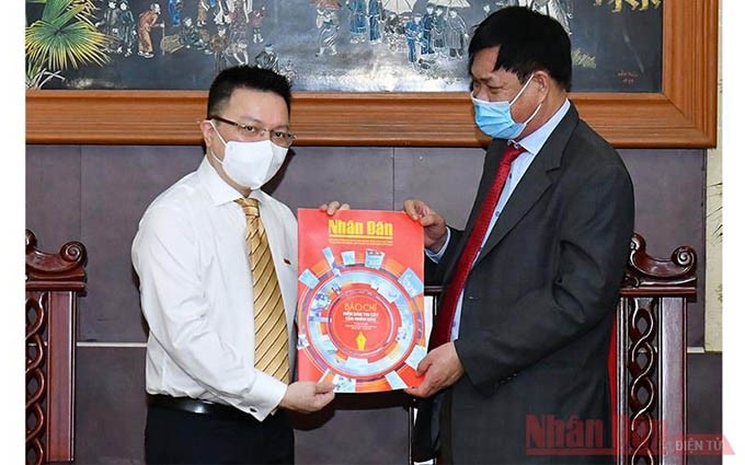  El jefe de Redacción del periódico Nhan Dan, Le Quoc Minh, regala al jefe del Comité del PCV en el Bloque de los Órganos Centrales, Huynh Tan Viet, la edición especial de Nhan Dan del 21 de junio. 