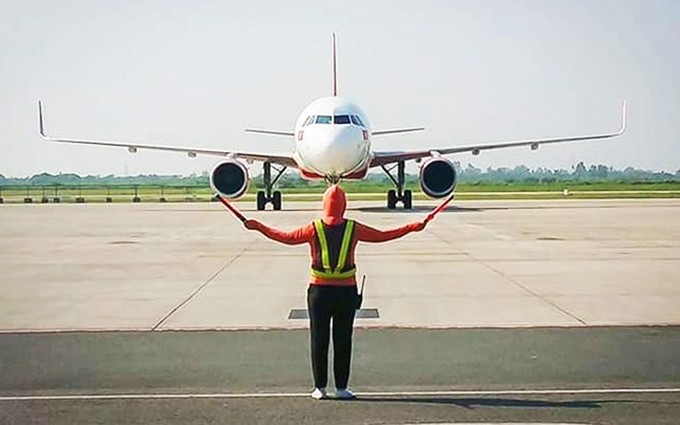 Una trabajadora del aeropuerto guía a un avión.