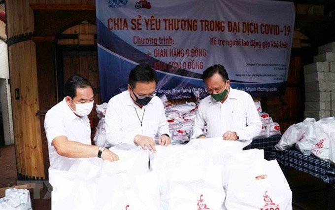 Phung Cong Dung, jefe del Comité sobre vietnamitas en el extranjero de Ciudad Ho Chi Minh (extremo derecho) y Le Ba Linh, expatriado tailandés, presidente de la empresa Pacific Foods (centro) examinan los regalos dedicados a los pobres.(Fotografía: VNA)