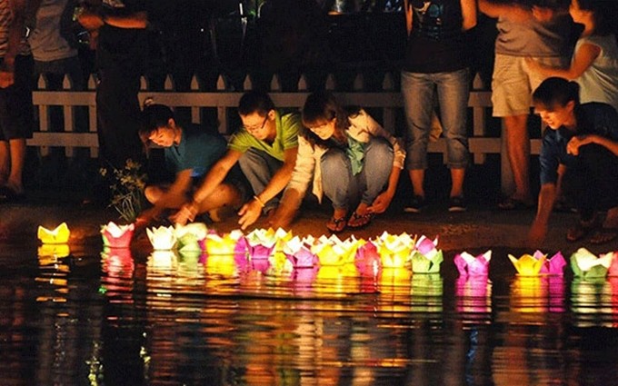 Los visitantes con sus velas de papel al lado del río Thu Bon.