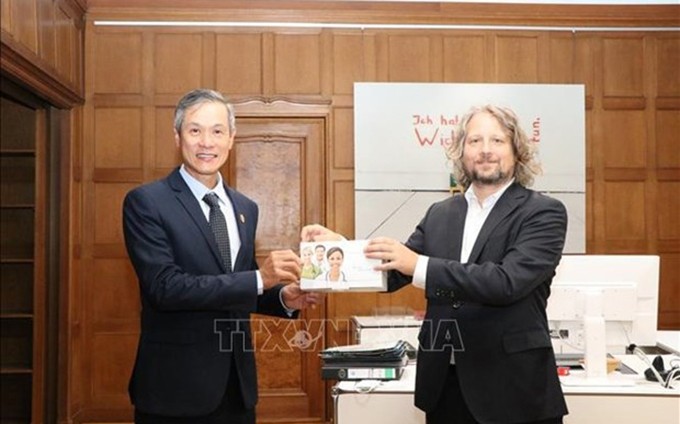 El embajador de Vietnam acreditado en Alemania, Nguyen Minh Vu, recibe la donación del secretario de estado del Departamento de Economía, Energía y Empresas Públicas del Senado de Berlín, Christian Rickerts.  (Fotografía: VNA)
