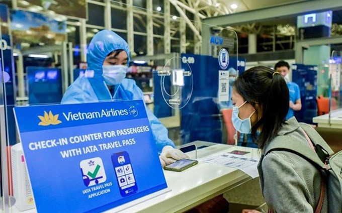 Se instruye a un visitante sobre cómo declarar su estado de salud en un punto de control de entrada (Foto: VNA)