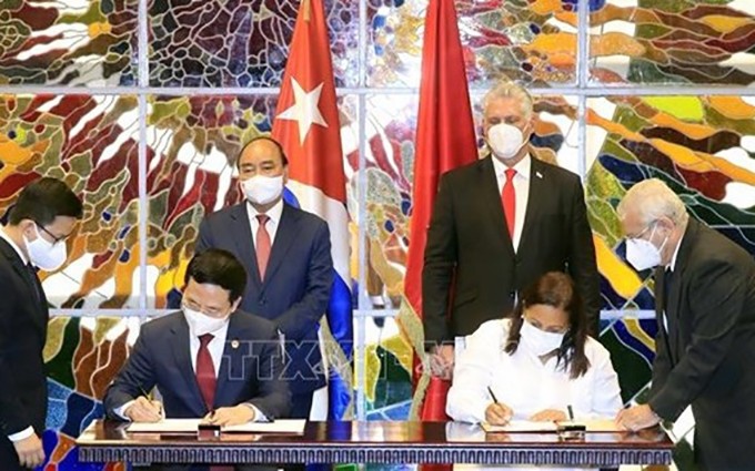 Los dos ministros de Vietnam y Cuba firman el documento al respecto. (Fotografía: VNA)