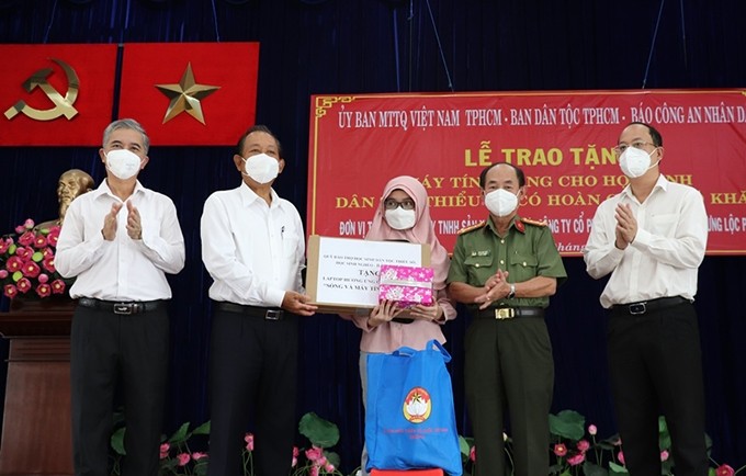 El ex vice primer ministro permanente Truong Hoa Binh (segundo desde la izquierda) entrega a estudiantes de la etnia Cham dispositivos al servicio del aprendizaje en línea. (Fotografía: Nhan Dan)
