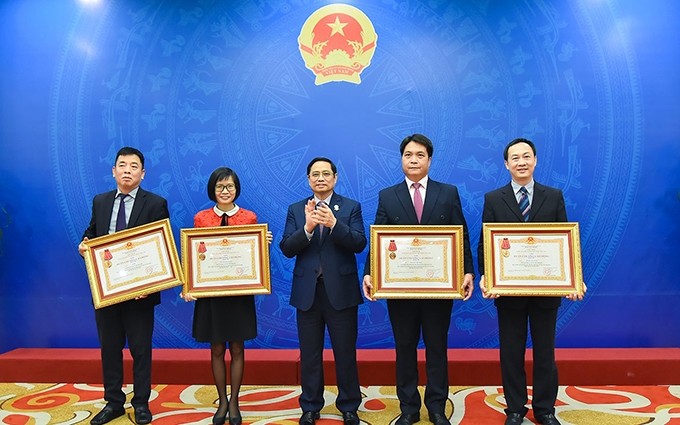 El primer ministro Pham Minh Chinh (medio) en la entrega del certificado de mérito a funcionarios destacados en la labor. (Fotografía: baoquocte.vn)