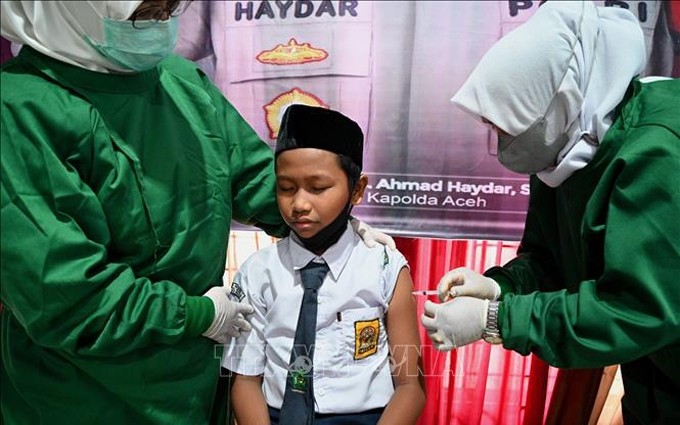 Personal médico administra la vacuna contra el Covid-19 a alumnos en Indonesia. (Fotografía: VNA)